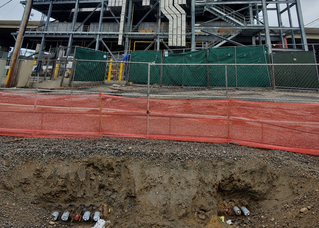 Microgrid power project under construction, with an excavation in the foreground exposing underground cables